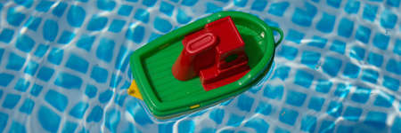 Small plastic toy boat floating in a swimming pool. Panoramic imageの写真素材