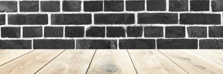 Empty wooden table with black brick wall in the background. Panoramic imageの写真素材