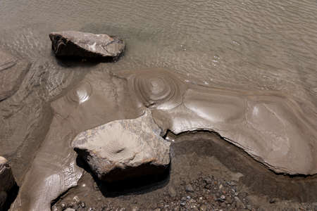 Close up view of the mud and stones near the water