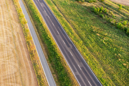 Empty asphalt road and bike lane between fields from aboveの写真素材