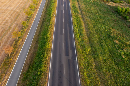 Empty asphalt road and bike lane between fields from aboveの写真素材