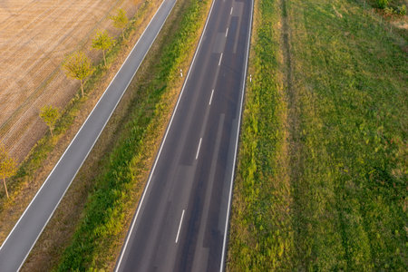 Empty asphalt road and bike lane between fields from aboveの写真素材
