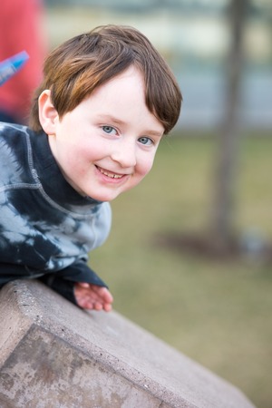 Young boy leaning over looking and smilingの写真素材