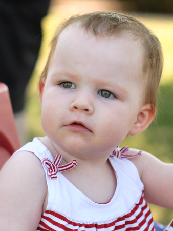 Young girl riding in red wagon having fun in the park for July Fourthの写真素材