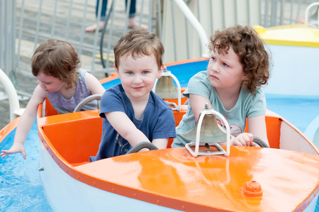 Young toddler sibblings having fun on boardwalk amusement rideの写真素材
