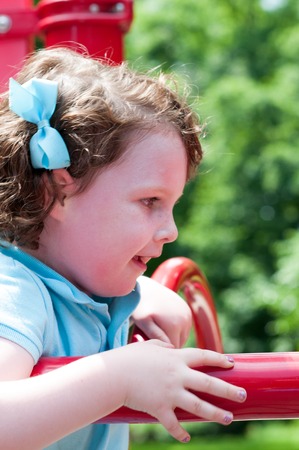 Young girl having fun outside at park on a playground swing setの写真素材
