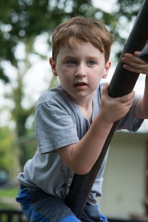 Young boy having fun outside at park on a playground climbing setの写真素材
