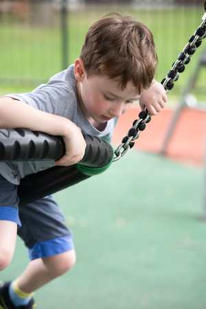 Young boy having fun outside at park on a playground climbing setの写真素材
