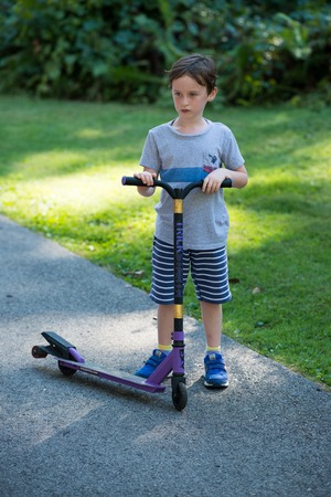 Young litte boy outside riding his scooter in the drivewayの写真素材