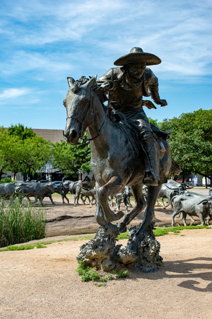 Dallas, Texas - May 7, 2018: Cowboy and longhorn cows with cattle in the background, as part of a landmark bronze cattle sculptureのeditorial素材