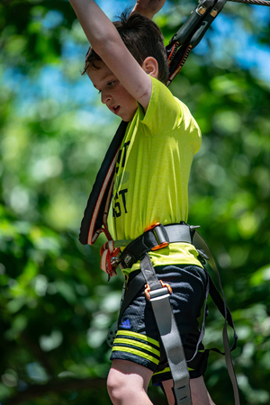Portrait of a handsome boy on a rope park among trees. Children summer activities.の写真素材