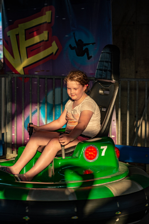 Happy young girl rides electric bumper car amusement ride on shore boardwalkの写真素材