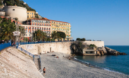 Nice, France February 6 2011: Castel beach on a sunny winter day with people walking on the promenade. Nice is a popular tourist city in the south of France.のeditorial素材