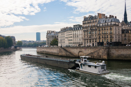 Paris, France Oct 3 2015: Barge traveling on the Seine River in Paris, France with beautiful classic French architecture buildings along the bank.のeditorial素材
