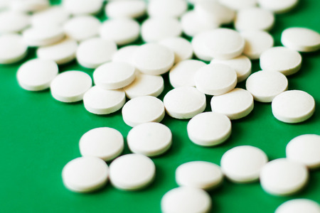 White pills on green background, differential focus