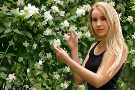Young blonde girl with long hair near blooming flowersの写真素材