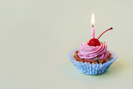 Birthday cake with cherry, pink cream and burning candle for birthdayの写真素材