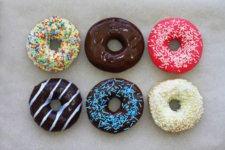 Donuts of different colors on cardboard, top viewの写真素材