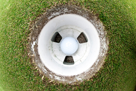 A view of a golf ball in the cup taken with a fisheye lens 