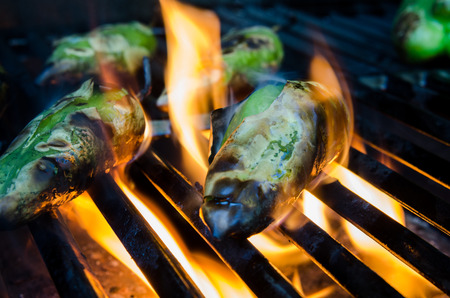 Small green peppers roast on flames on a grillの写真素材
