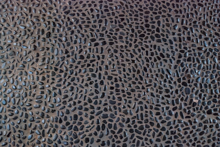 Small black pebbles scattered across cement in an outdoor walkwayの写真素材