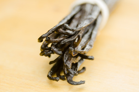A bound group of vanilla beans against a bamboo butcher block