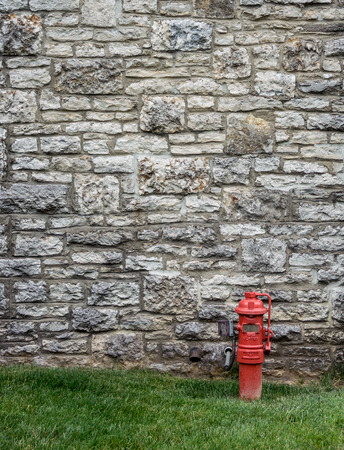 A red fire hydrant contrasts against an aged stone wall at a distillery along the bourbon trail