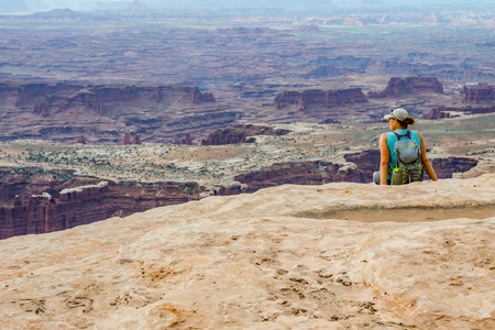 A female hiker looks out over a vast canyon on a hike in Utah