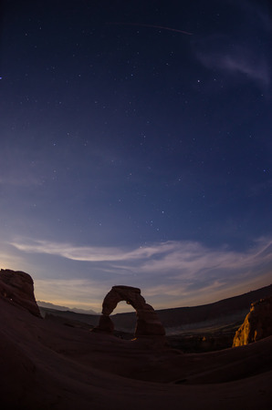 The silhouette of delicate arch as night falls over the desert with a fisheye lens