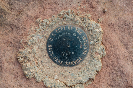 A metal marker embedded in concrete along a cliffのeditorial素材