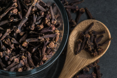 Glass Bowl of Cloves with wooden spoon in backgroundの写真素材