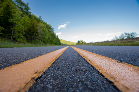 Extreme Low Angle of Yellow Road Stripe on a mountain road in summerの写真素材
