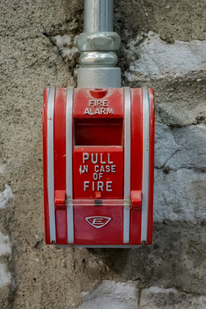 A metal red and silver fire alarm box inside a distillery