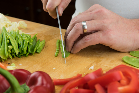 Close Up of Snow Peas Being Sliced on wooden butcher blockの写真素材