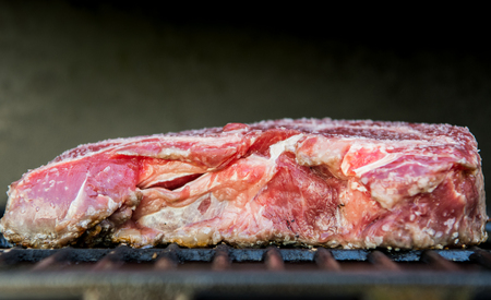 Raw Steak Cooks on Hot Grill in a summer cookout