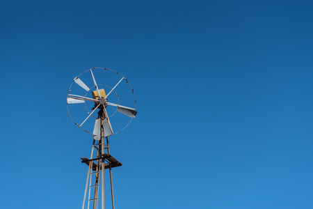 Rusted Windmill in the Desert on Blue Skyの写真素材