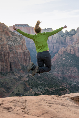 Woman Leaps High in front of vast canyon in late afternoonの写真素材