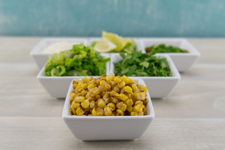 Roasted Corn in White Bowl in front of other seasoningsの写真素材
