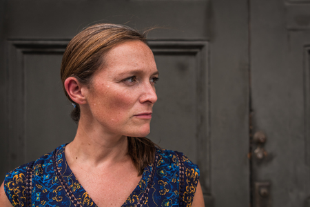 Brunette Middle Aged Woman Looks to Side in front of wooden doorの写真素材