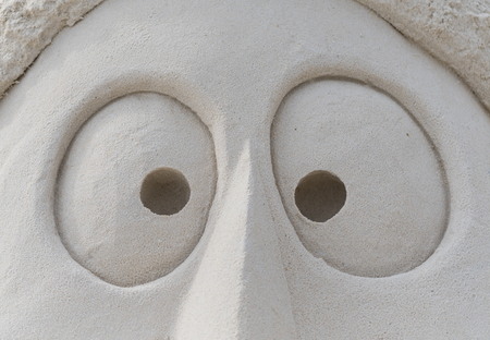 Eyes in Sand on face sand sculpture close upの写真素材