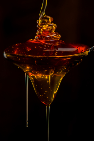 Large Glob of Honey Falls from Spoon against dark backgroundの写真素材