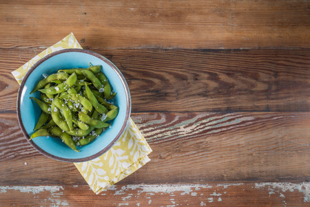Salted Edamame in Blue Bowl With Large Copy Space over wooden tableの写真素材