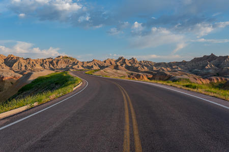 Road Winds Through Badlands Rock Formations on Early Summer Morning