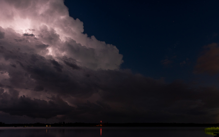 Lightening Brights up Cloud in Night Storm Across Calm Lake
