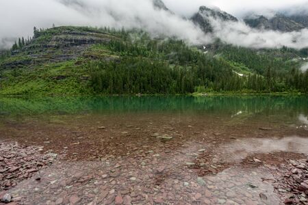 Clear Water of Avalanche Lake with fog along the mountain shoreの写真素材