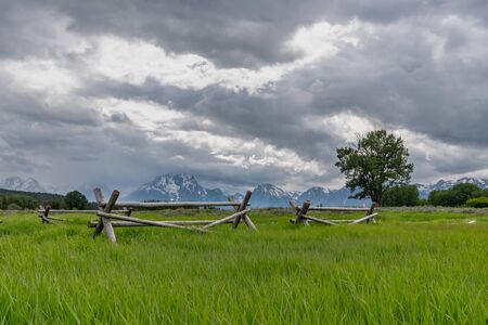 Wooden Fence in Field in Front of Tetons Mountain Rangeの写真素材