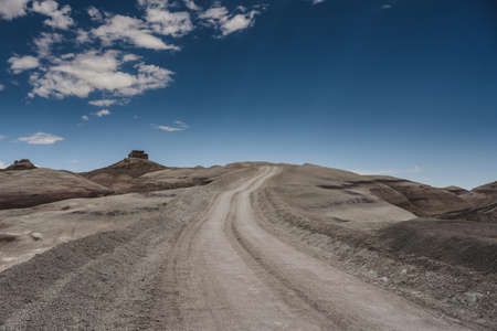 Dirt Road cuts into desert ground on blue sky sayの写真素材