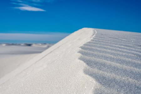 Sparkling White Sand Dune Crest Against Blue Skyの写真素材