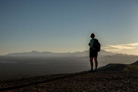 Female Hiker Stands At Cliff Edge Looking Over Saguaro National Park