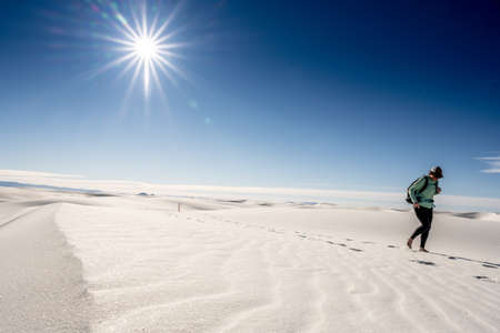 Female Hiker Crosses Sand Dune with Sun Burst At Her Back in White Sands National Parkの写真素材